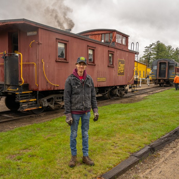 a train engine carrying carts down a track in front of a house