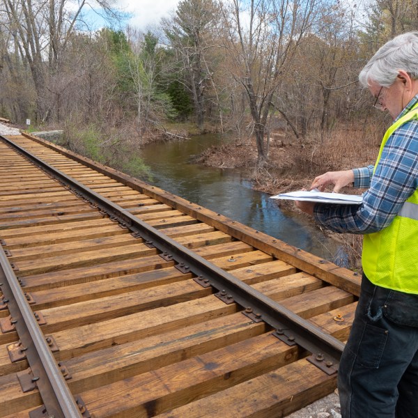 a man standing on top of a wooden fence