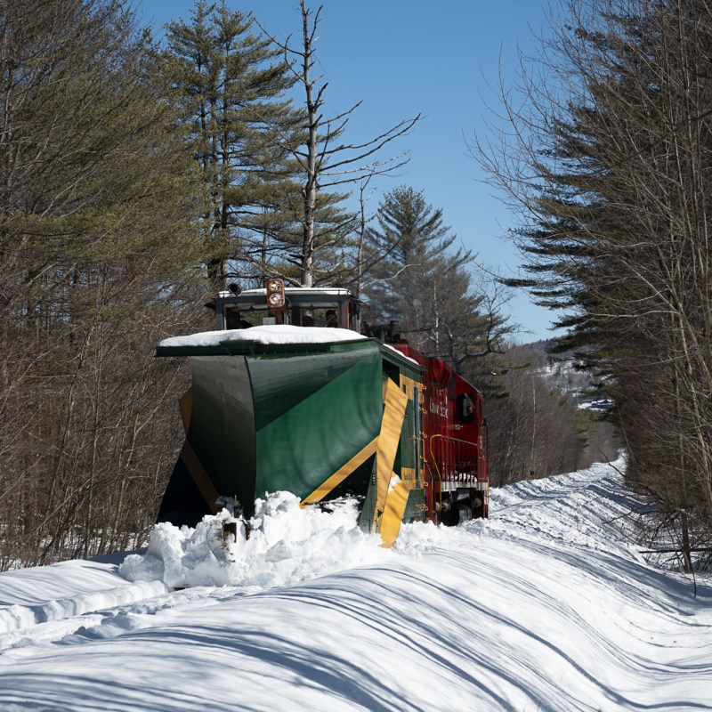 a man riding a snowboard down a snow covered forest