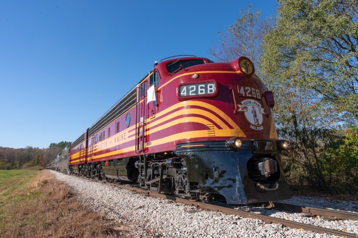 Vintage train with red and yellow stripes on railway in countryside.