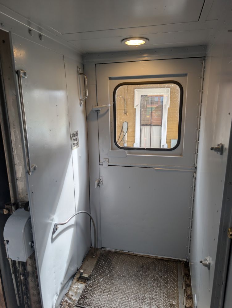 Interior view of a train vestibule with a door and window.