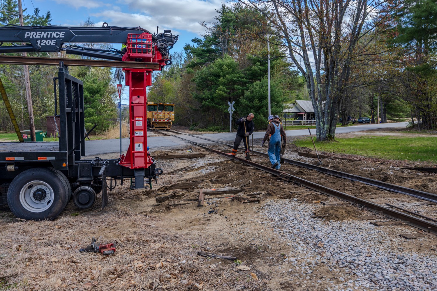 Two workers repairing railroad tracks with equipment nearby.