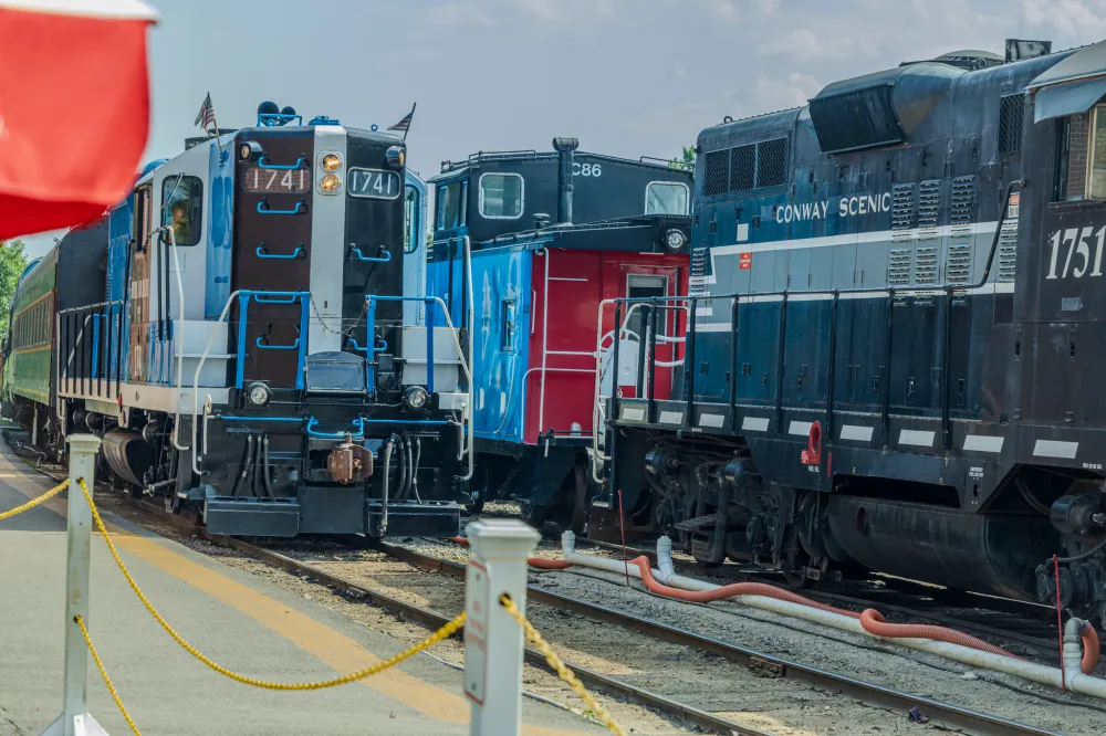 Three colorful trains parked side by side on tracks.