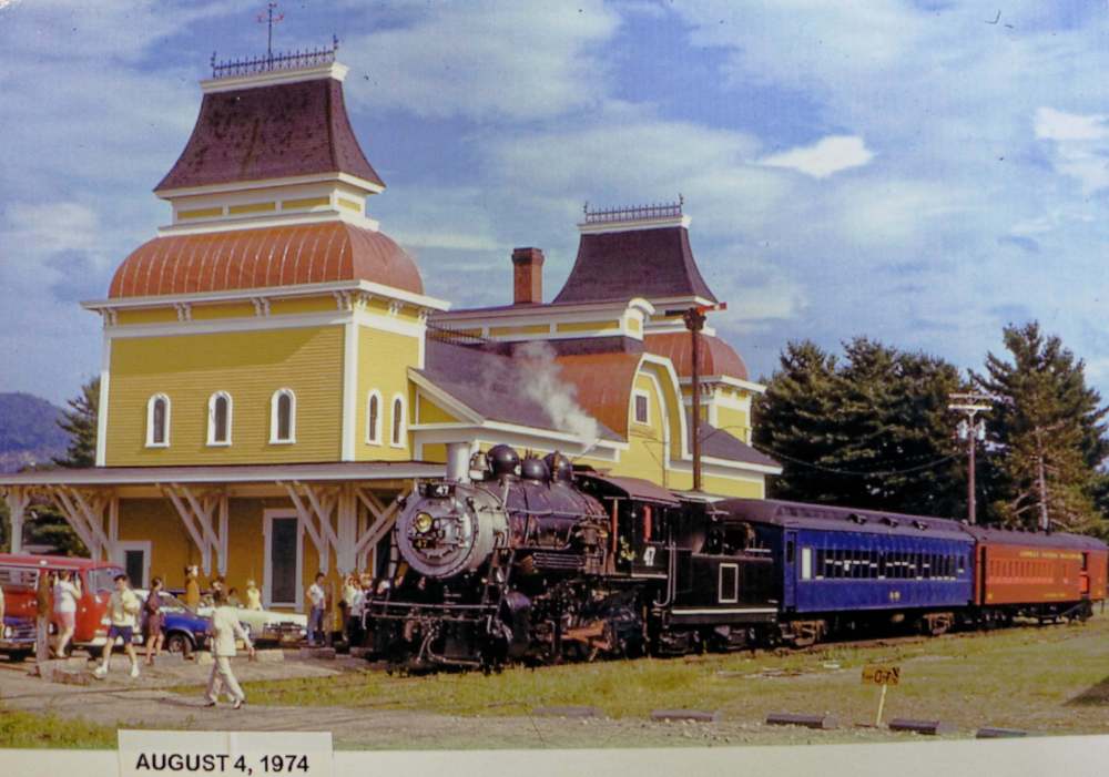 Vintage train at a station with yellow building, dated August 4, 1974.