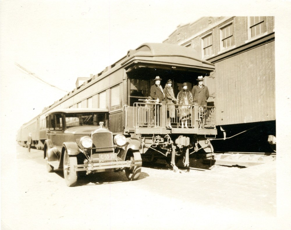 Vintage car and people on train platform in sepia tone